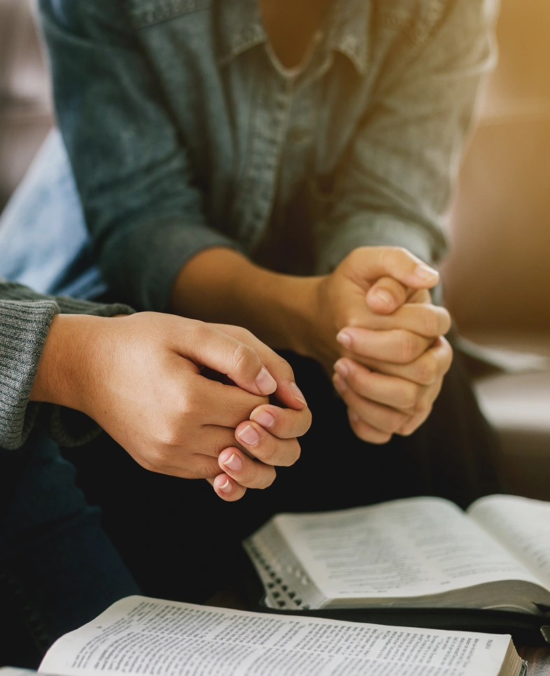 People holding hands over open book.